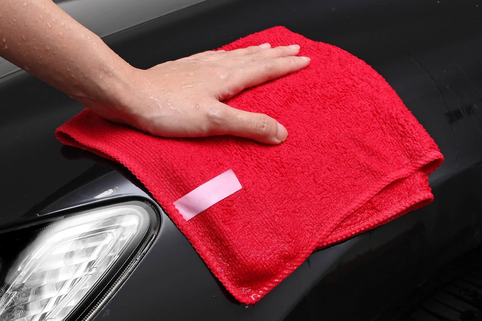 Wiping the headlights of a car with a red towel