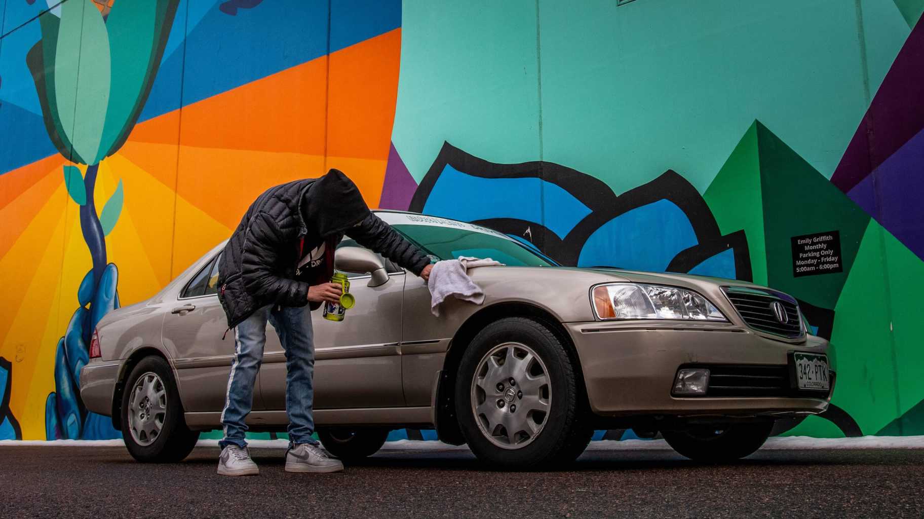 A man wiping a shiny car outdoors