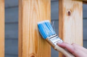 A blue paint brush shining the wood