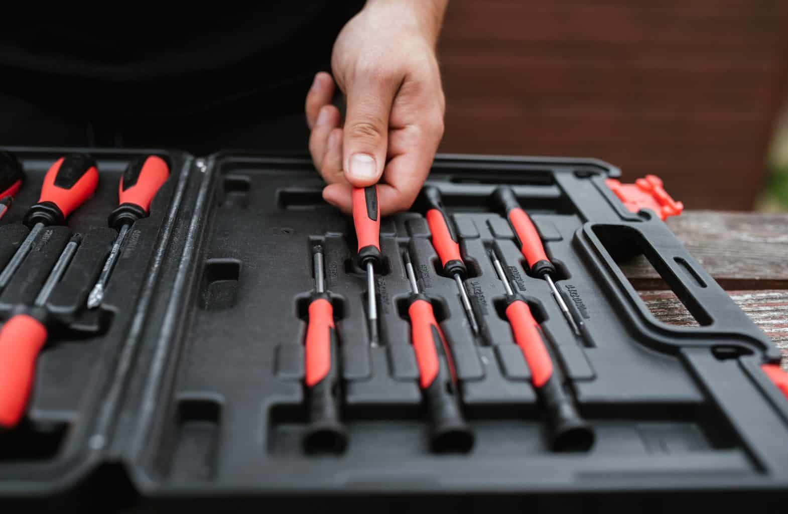 A hand pulling a screwdriver out of a toolbox