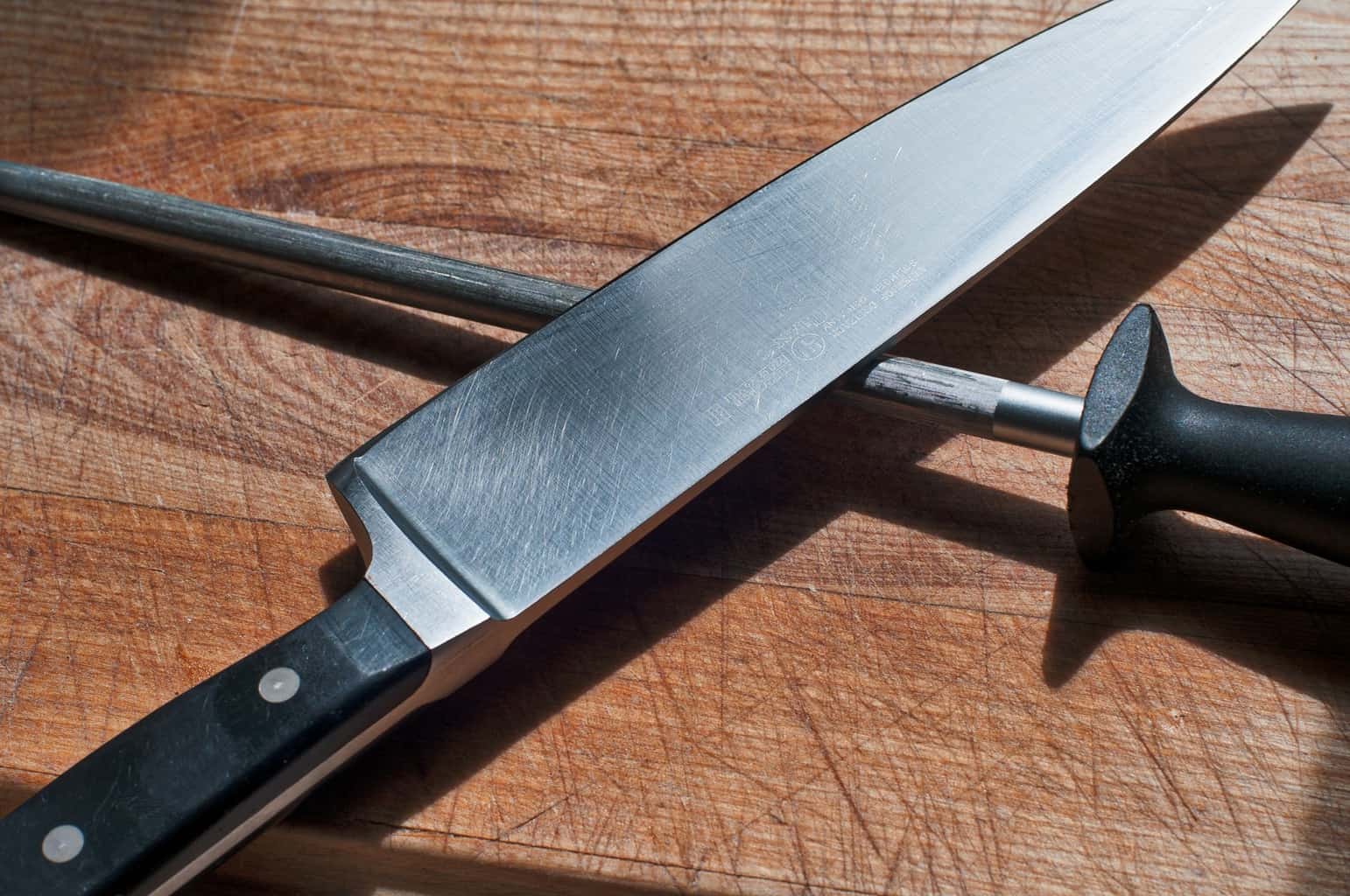 A knife and sharpening stick on wooden table