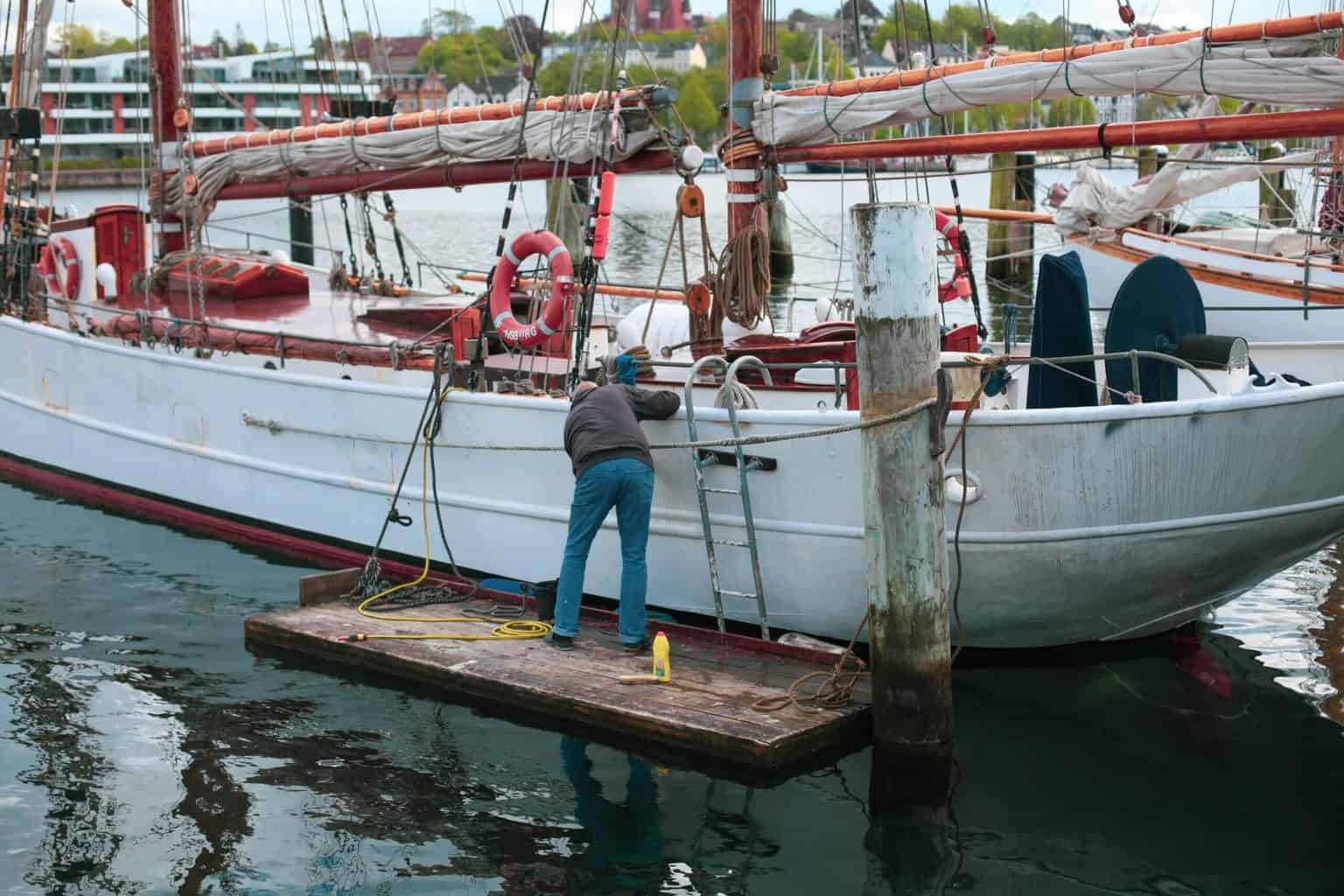 People trying to clean a white boat