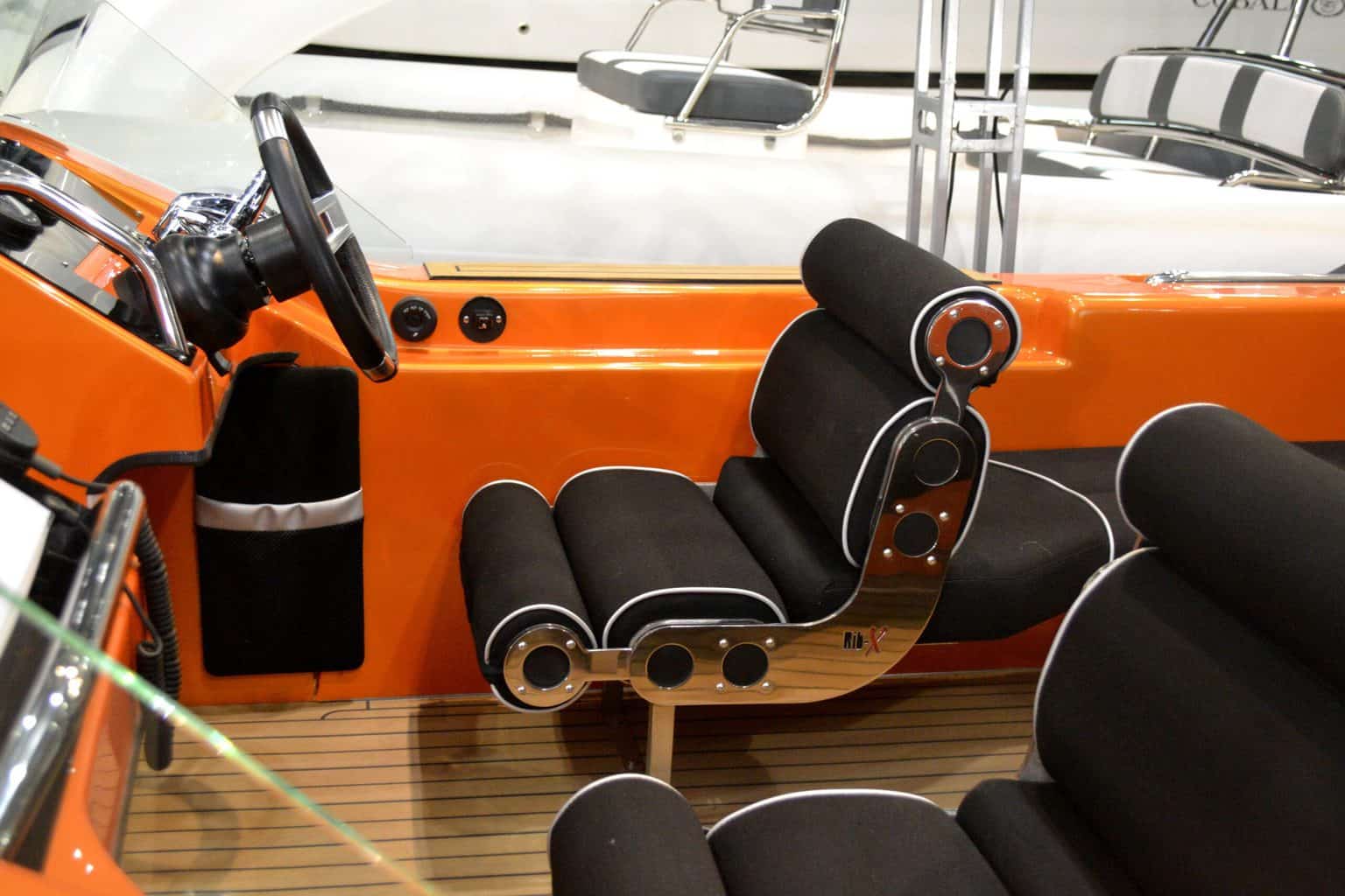 A black boat seat with the steering wheel