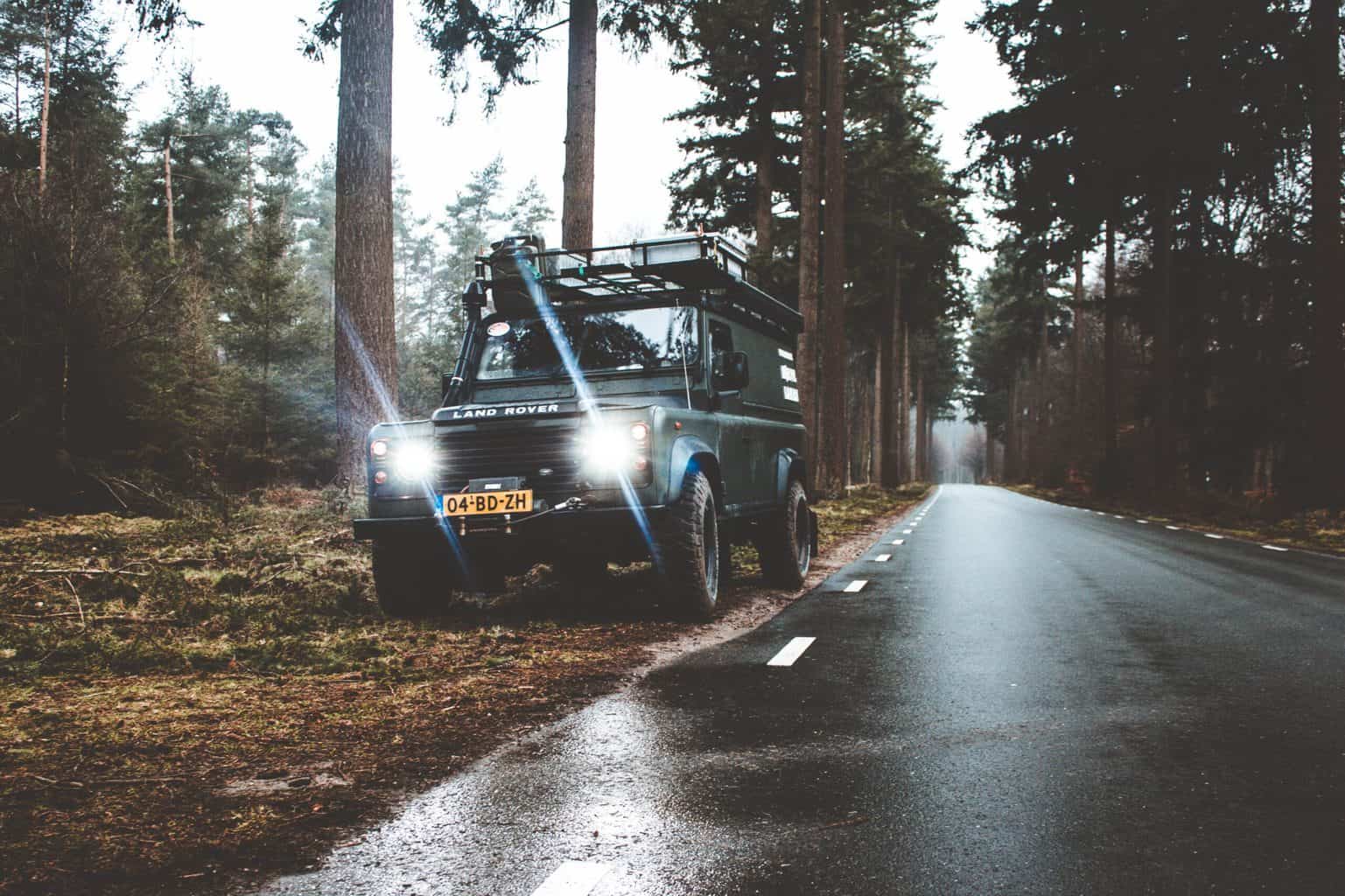 A jeep wrangler with a roof rack and switched on headlights