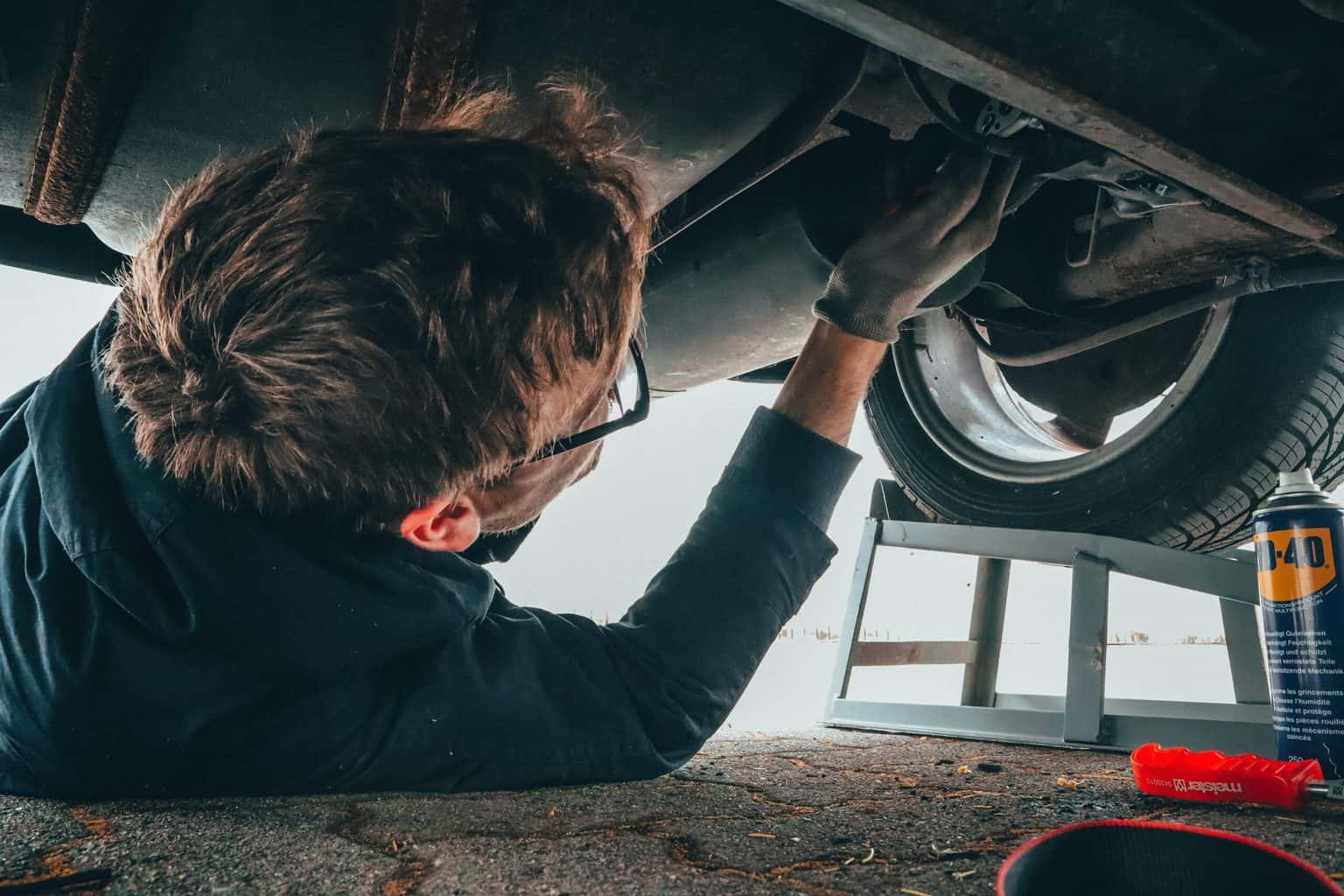 A man under the vehicle fixing an engine