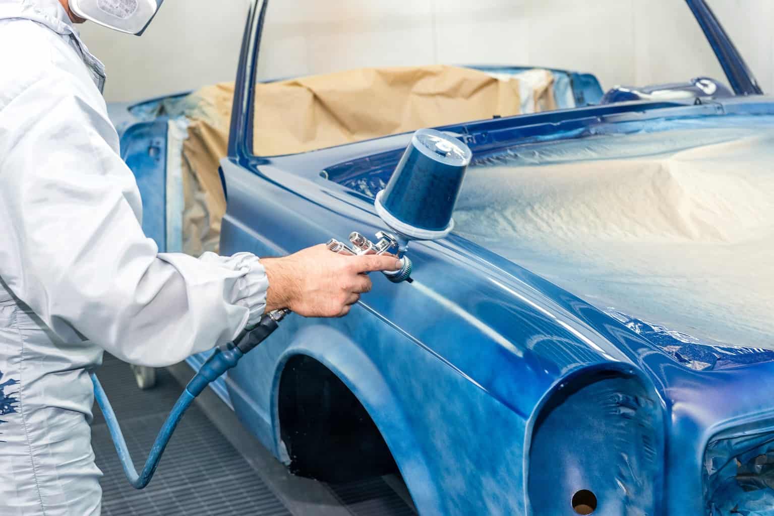 Spraying a blue color to a car with a powder coating gun