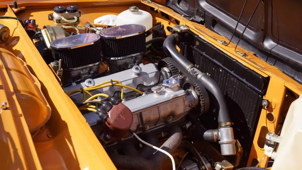 An old car engine with small oil deposits in a yellow car