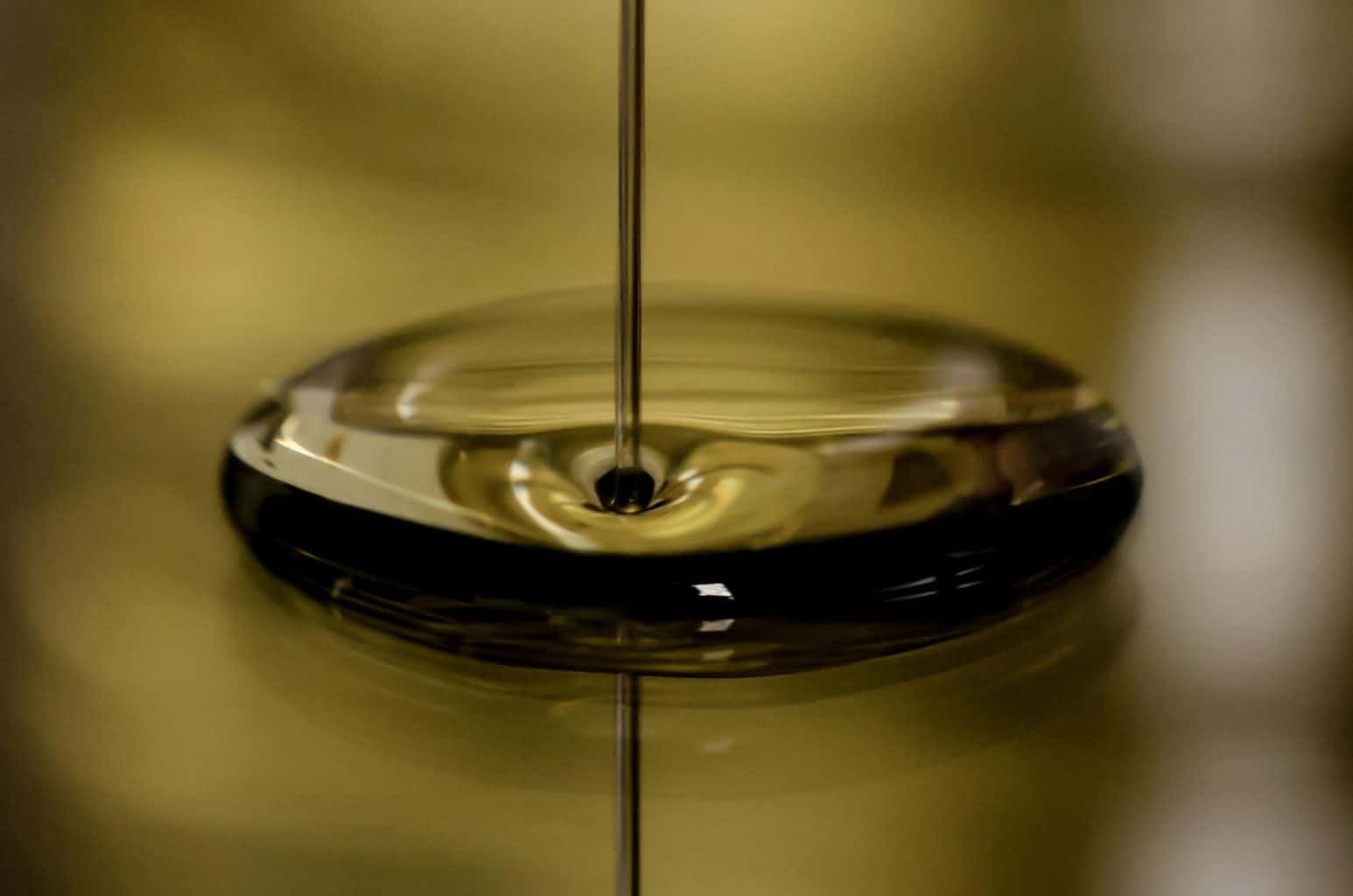 An oil being poured on a gold surface