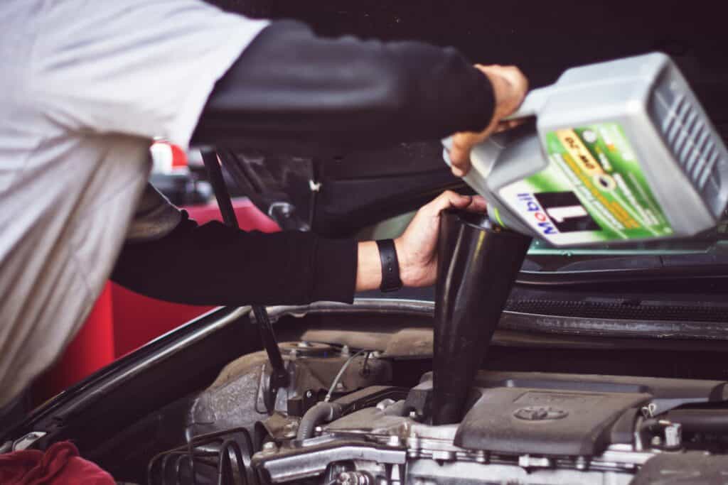 Pouring oil to the engine with a black funnel