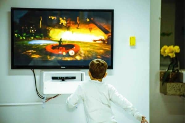 A child watching a TV mounted on a drywall