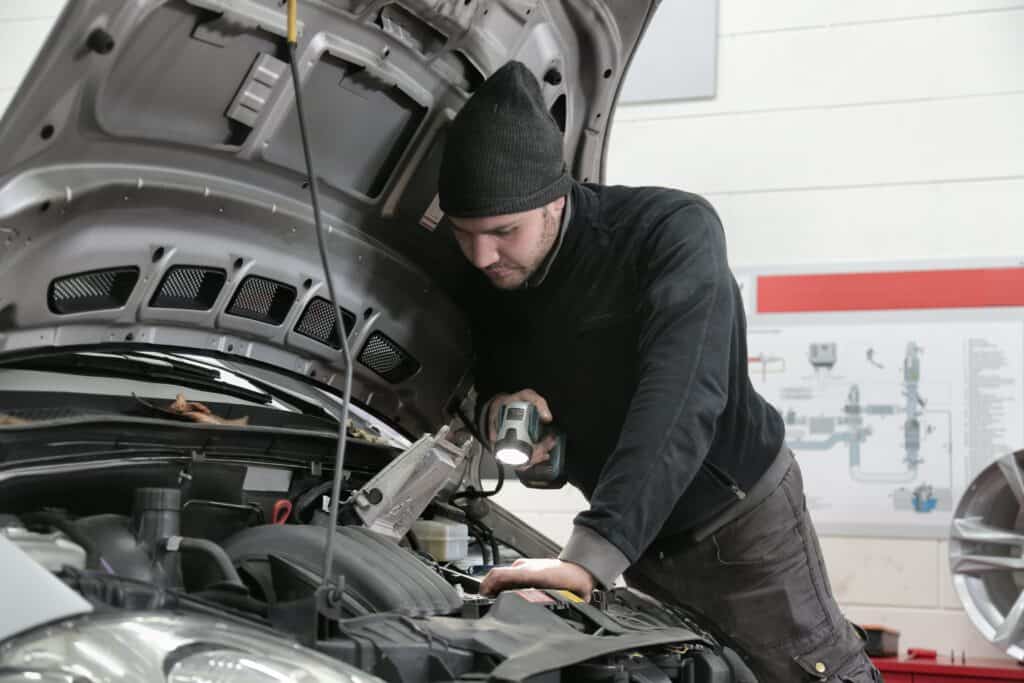 A mechanic checking a car engine with a flashlight