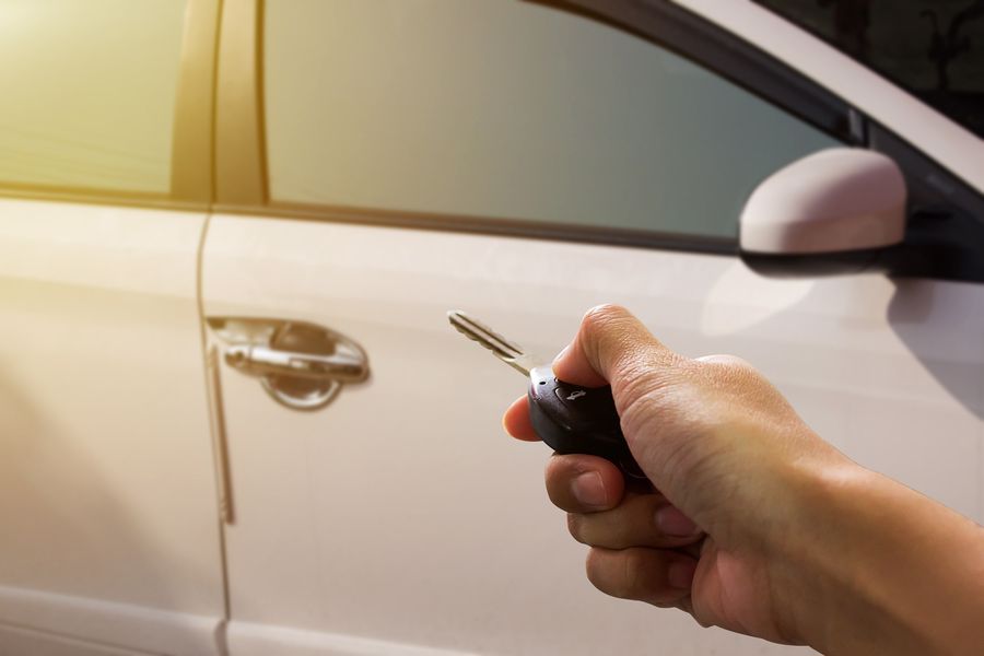 Hand holding car keys near a car